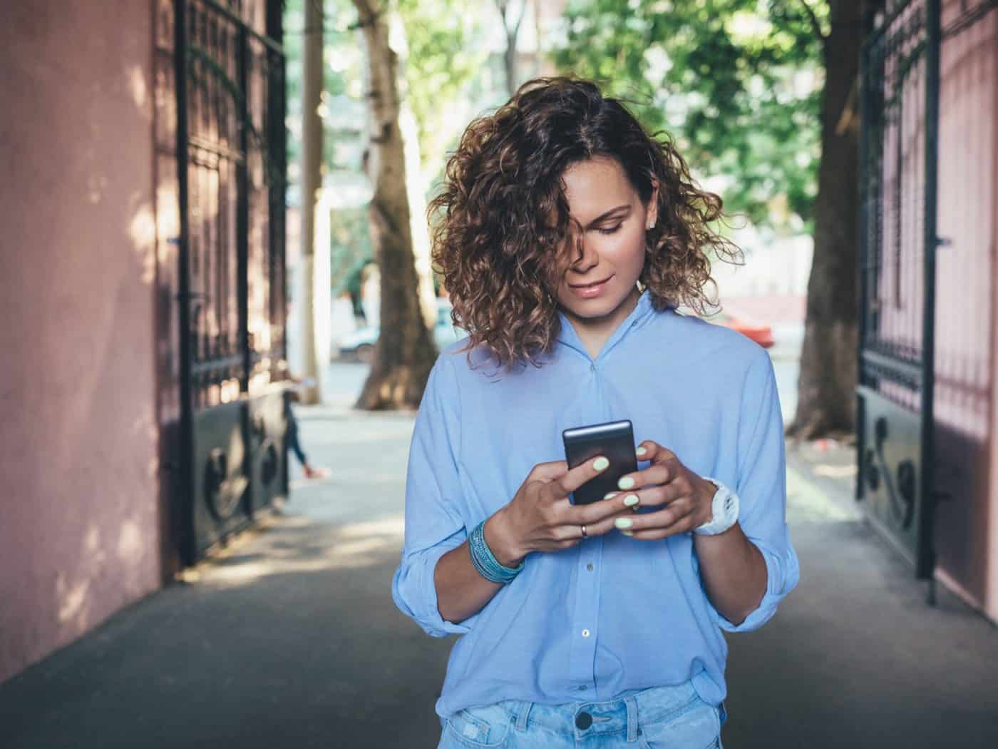 woman with curly hair looking at her phone