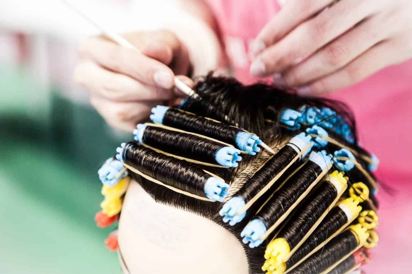 A person perming a woman's hair.