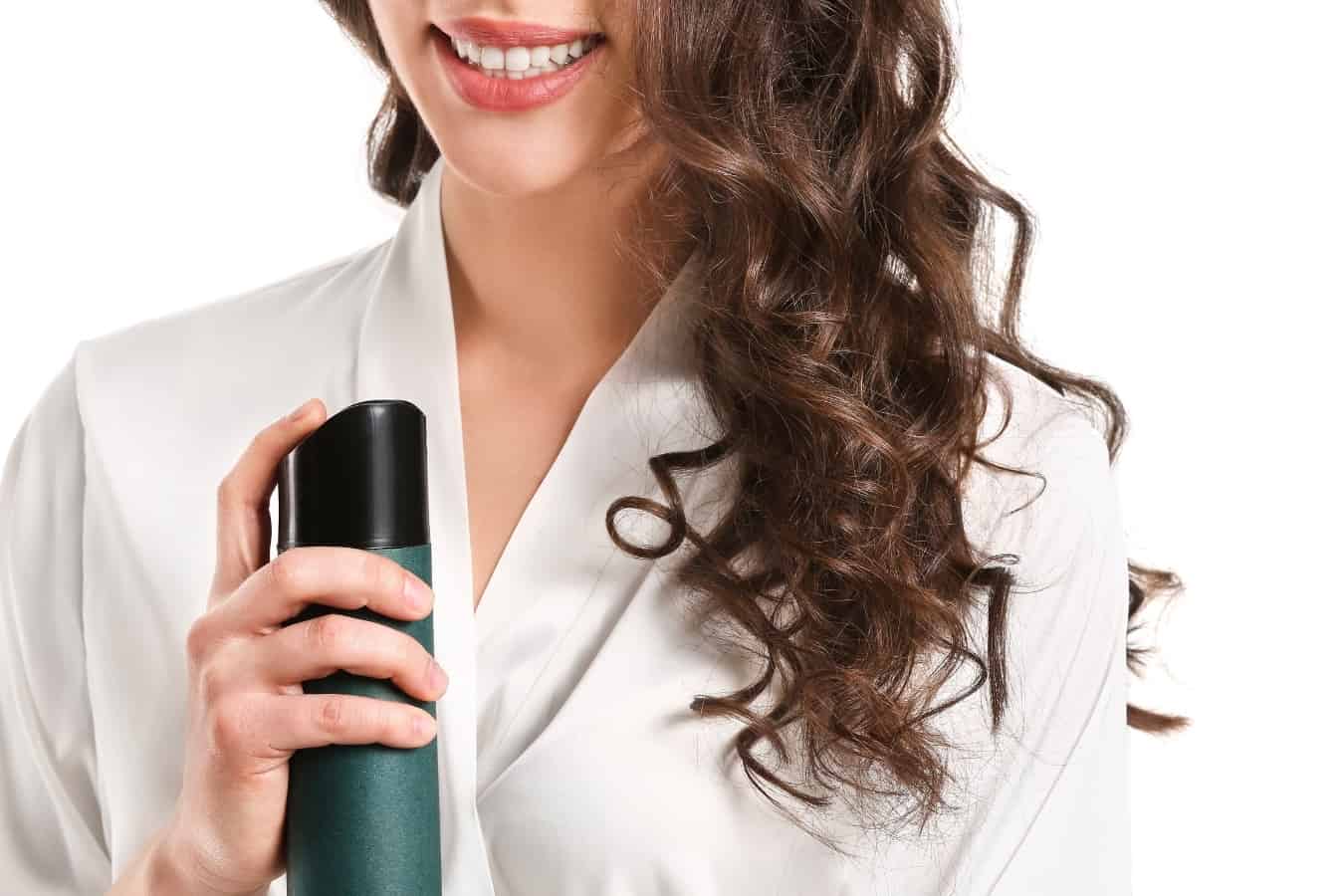 woman with long curly hair holding a hair spray
