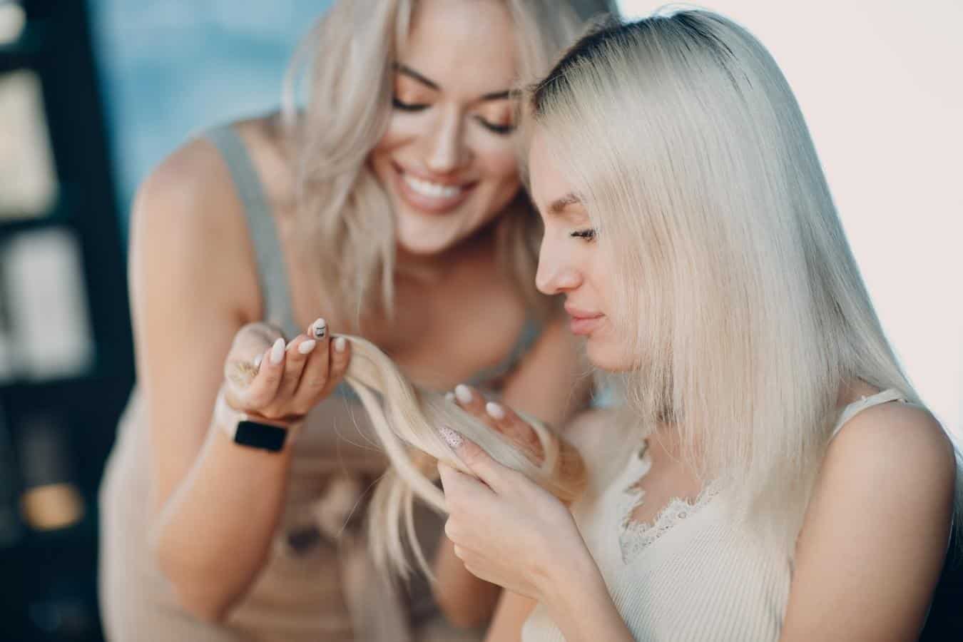 Two women looking at the ends of their hair