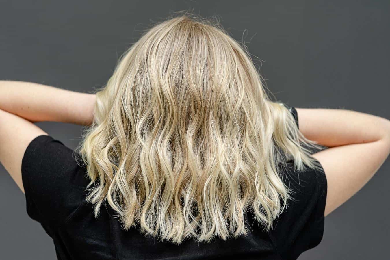 blonde woman is standing against a gray background 