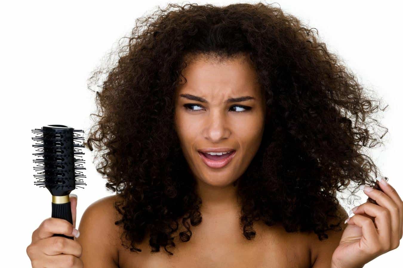 woman looking confused touching her hair and holding a brush in her hand