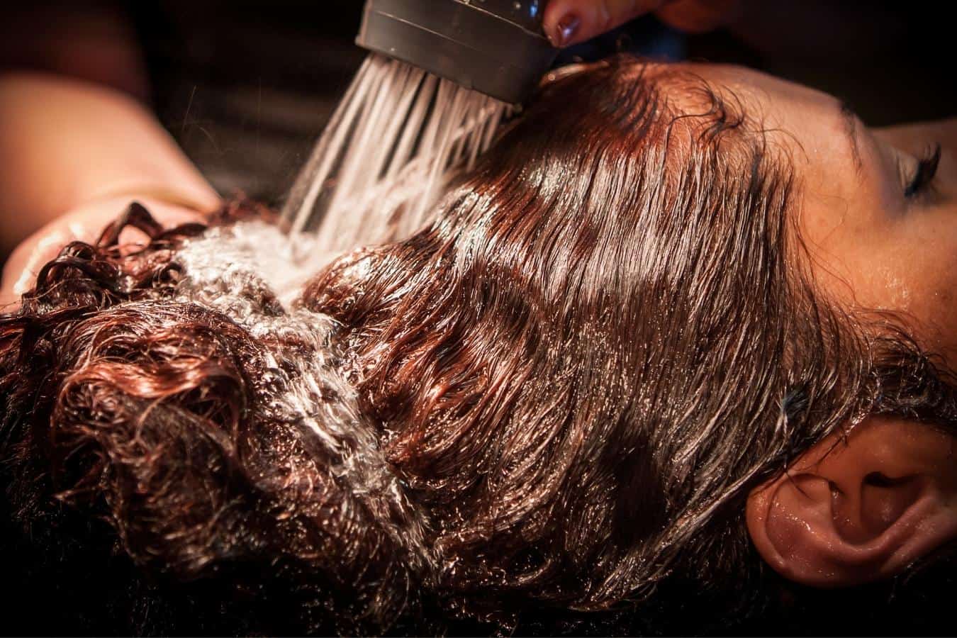 woman with copper brown hair having her hair washed